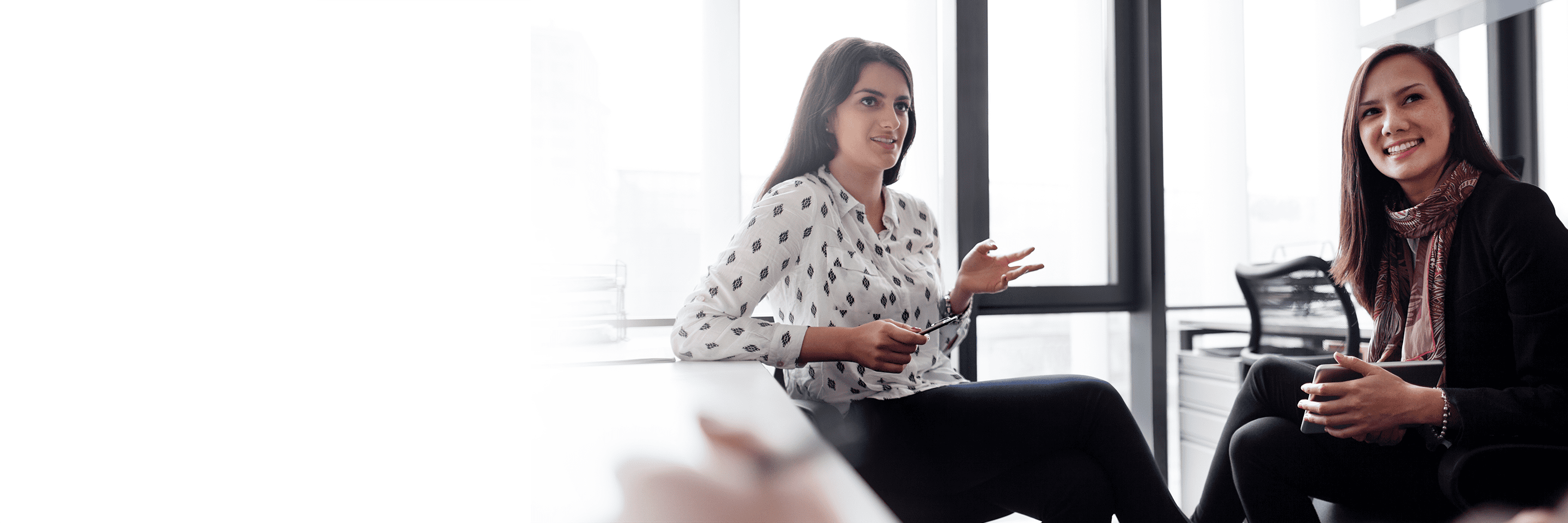 Photograph of two women in business attire brainstorming together